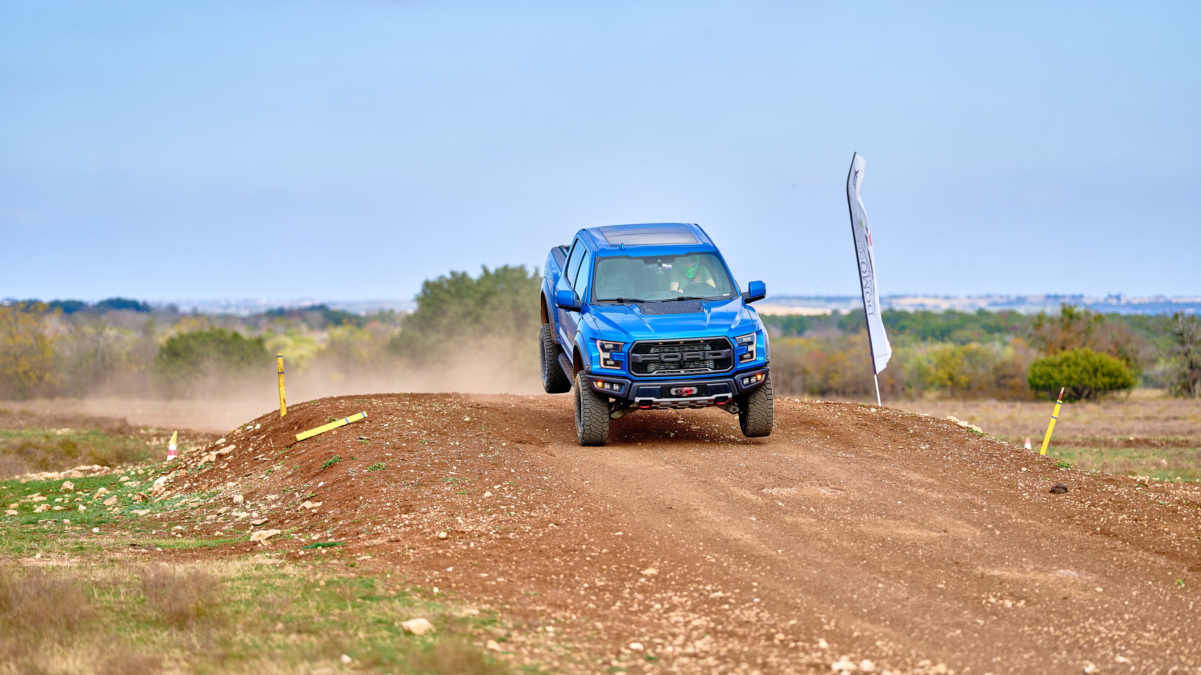 Ford Raptor cresting dirt mound at speed